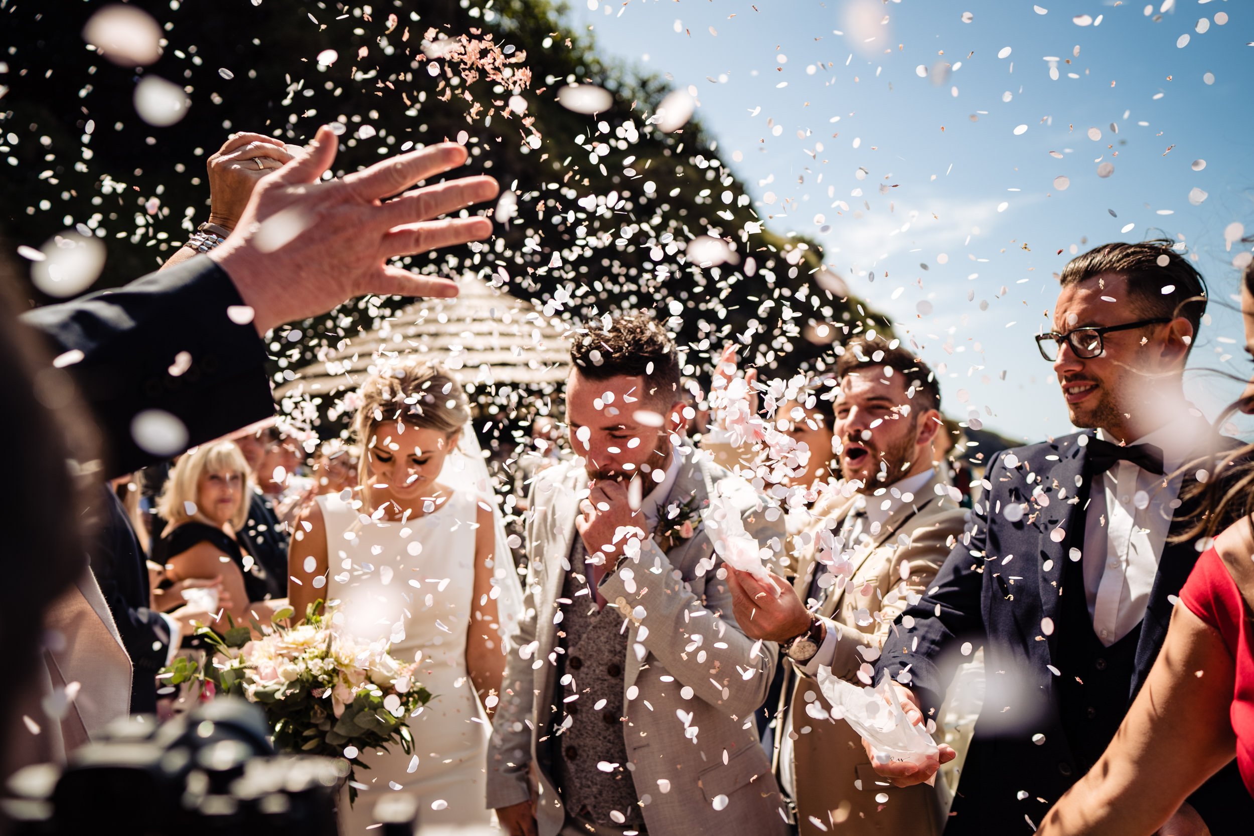 Newlyweds celebrate their wedding day as guests shower them with confetti. Joyful wedding celebration.