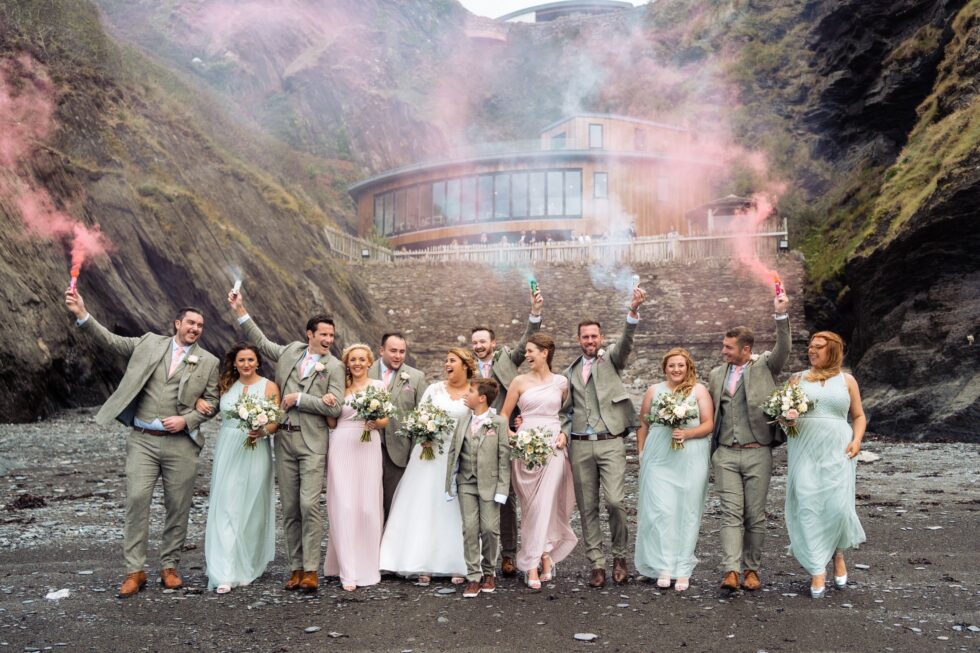 Bridal party with smoke bombs at Tunnels Beaches. Yeti Wedding Photography, North Devon beach wedding.