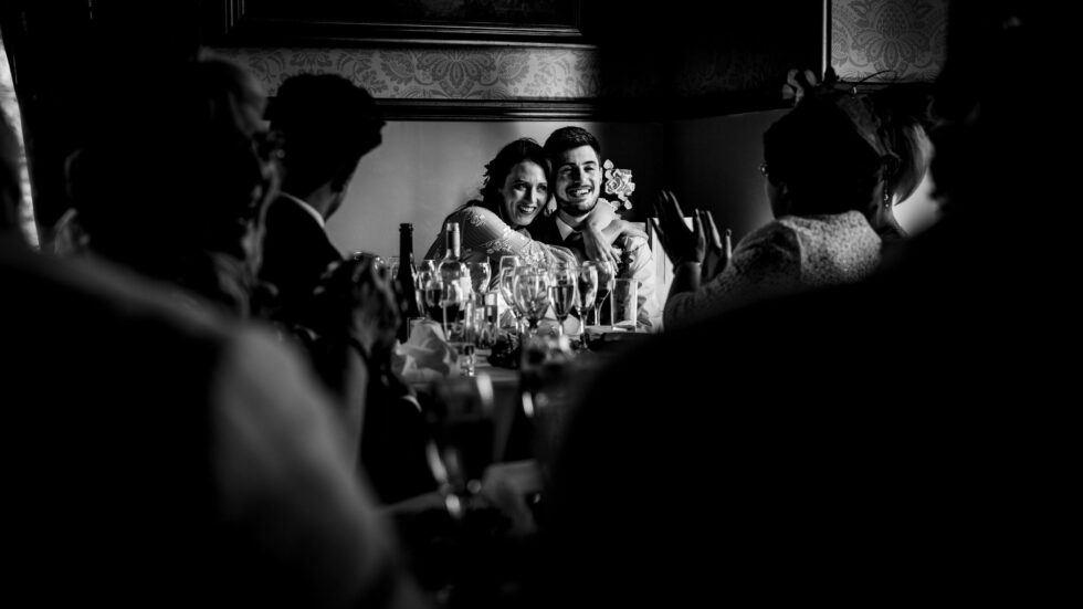 Black and white wedding photo of bride and groom during speeches. Yeti Wedding Photography.