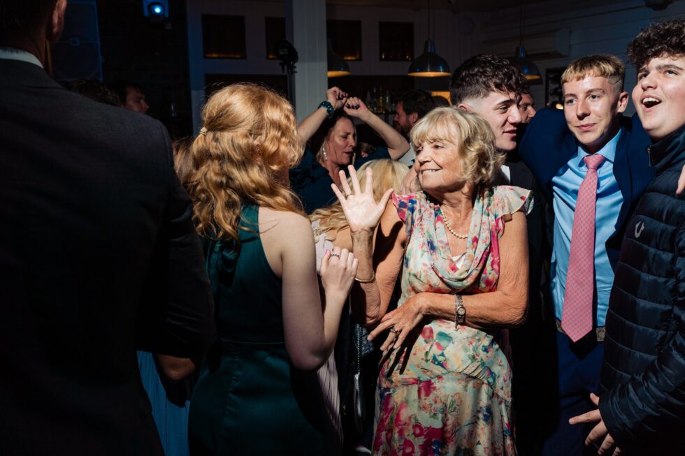 Wedding guests dancing in Devon. Yeti Wedding Photography captures fun moments, including older woman enjoying the party.