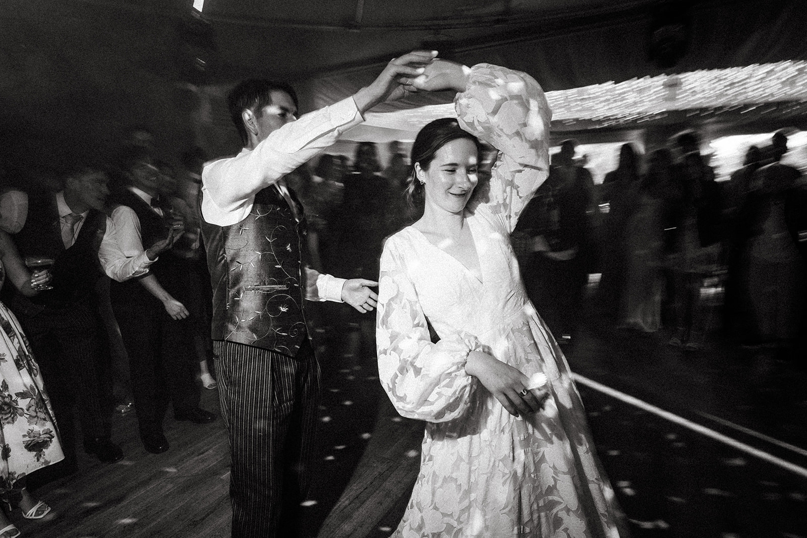 Bride and groom dancing together on the dance floor during a wedding reception, surrounded by guests in formal attire.